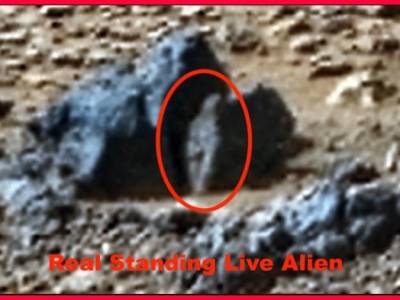 Un alienígena bípedo de 20 centímetros de altura, de pie en Marte, observa un rover en una foto de la NASA